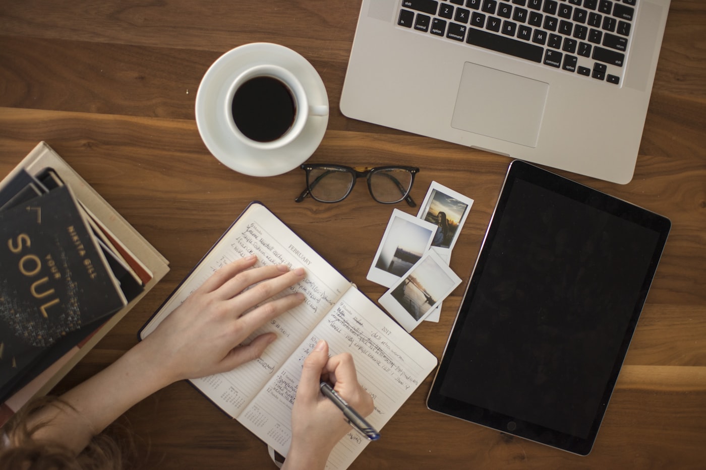 Hands writing on paper next to a laptop — editing website sentences until they sound like a person