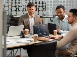 A professional business consultation meeting in a modern Dubai corporate boardroom discussing software requirements.